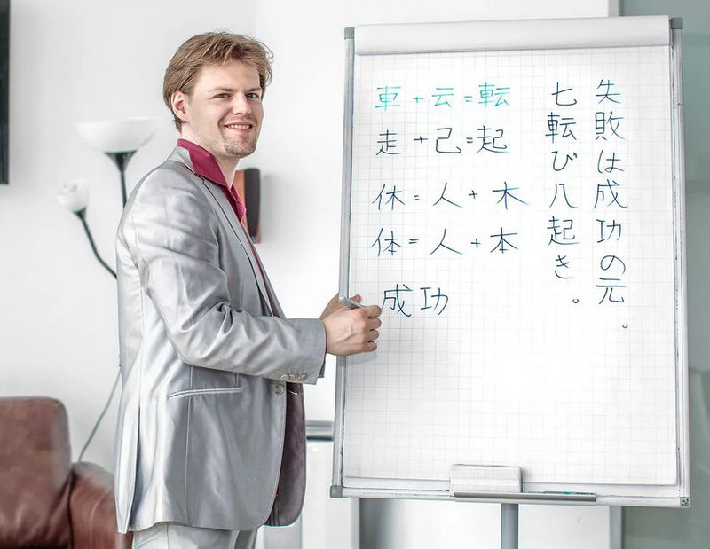 Мужчина пишет японские иероглифы бумаге